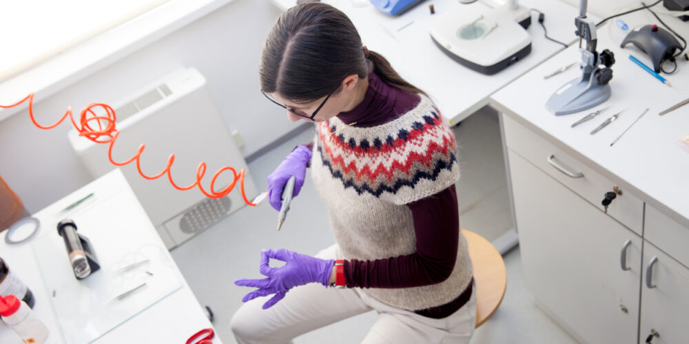 Woman Researcher Blowing Air at Scientific Sample With Compressor.